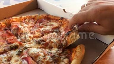 男人`手从打开的盒子里拿一片热的美味的意大利披萨，<strong>送餐</strong>服务，餐饮理念，近距离观看。